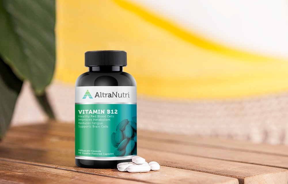 A bottle of AltraNutri Vitamin B12 capsules sits on a wooden surface with several white capsules scattered in front. A green leaf and a yellow-and-white background are visible.