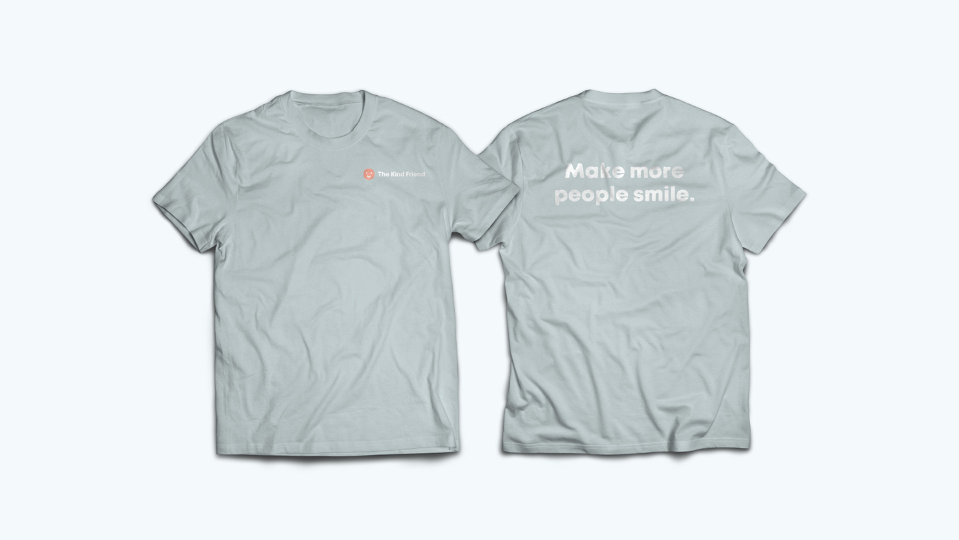 Two light gray t-shirts are displayed; the front shows a small logo and text on the left chest, while the back features the large white text Make more people smile.