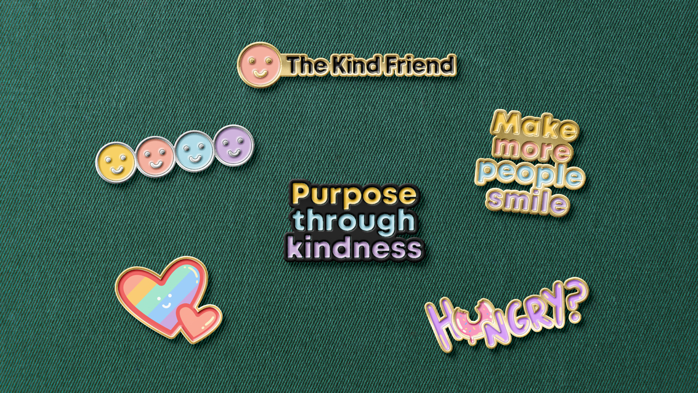 A green fabric background with colorful enamel pins designed by Sandra Tay.