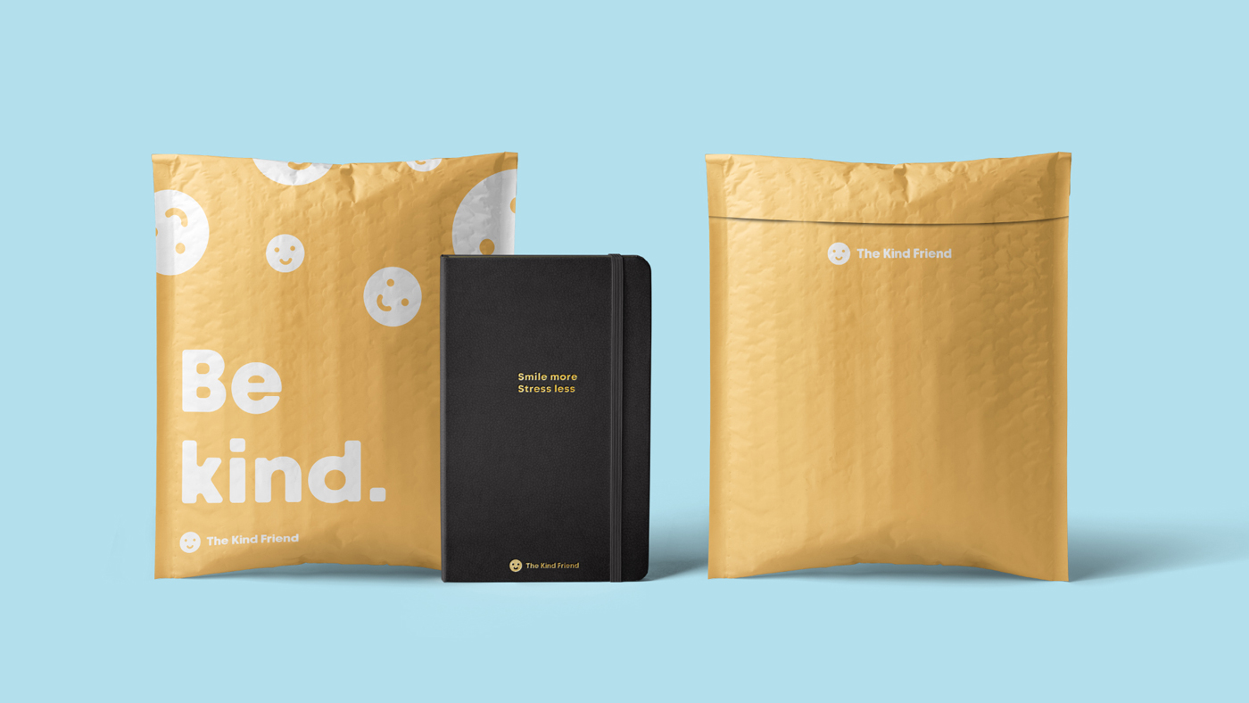 Two yellow padded envelopes designed by Sandra Tay with smiley faces and “Be kind.” text are placed beside a black notebook that reads “Smile more. Stress less.” on a light blue background.