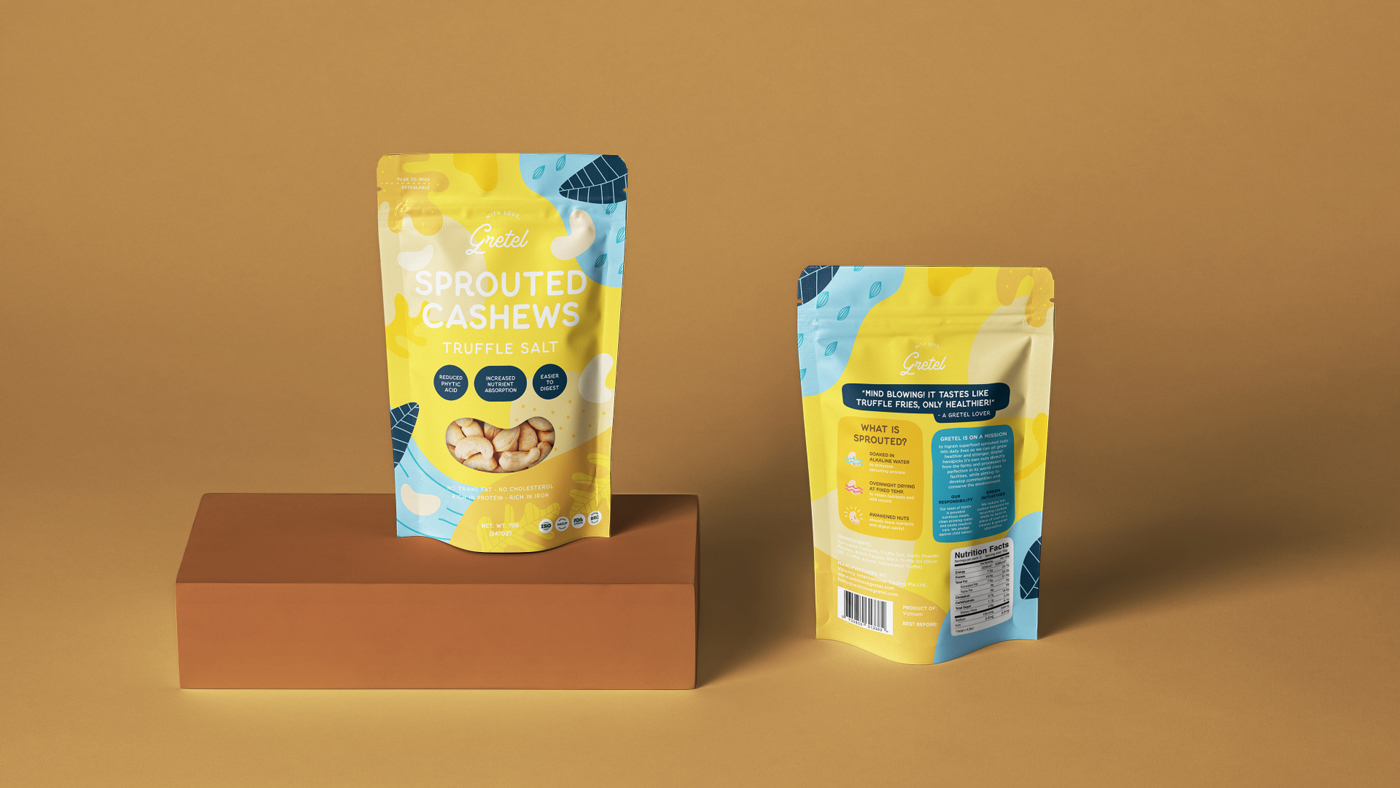 Two colorful yellow and blue pouches of sprouted cashews with truffle salt designed by Sandra Tay displayed on a brown block against a matching brown background. One pouch shows the front label, and the other shows the back label and nutrition facts.